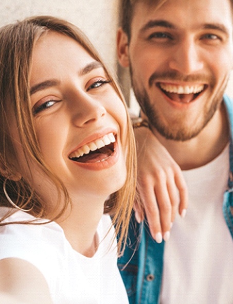 A young woman and man smiling and laughing together after seeing a cosmetic dentist in Myrtle Beach