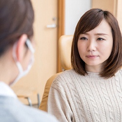 A young female sitting in the dentist’s chair and listening to her dentist discuss why she needs a dental crown