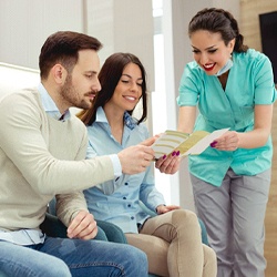 A couple discussing with a dentist about the cost of receiving a dental crown and looking over information about the procedure