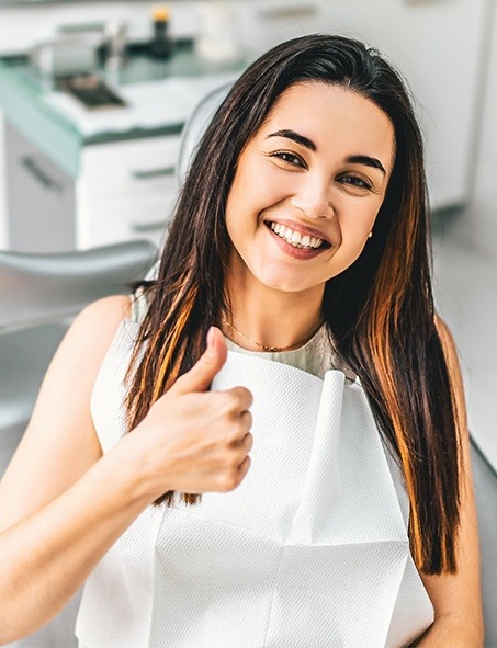 Smiling woman in dental chair giving thumbs up