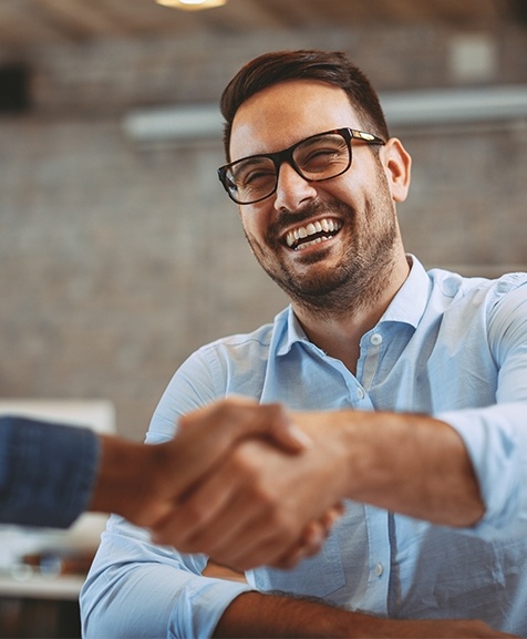 Laughing man shaking hands with team member