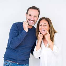 man and woman pointing to their smiles