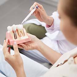 dentist showing a patient a model of a dental implant