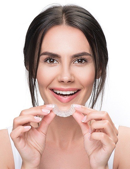 Smiling woman holding Invisalign in Myrtle Beach