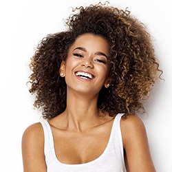 Woman smiles after getting teeth whitening after Invisalign