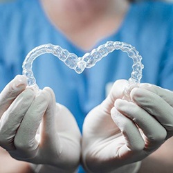 Dentist holding Invisalign aligners in heart shape