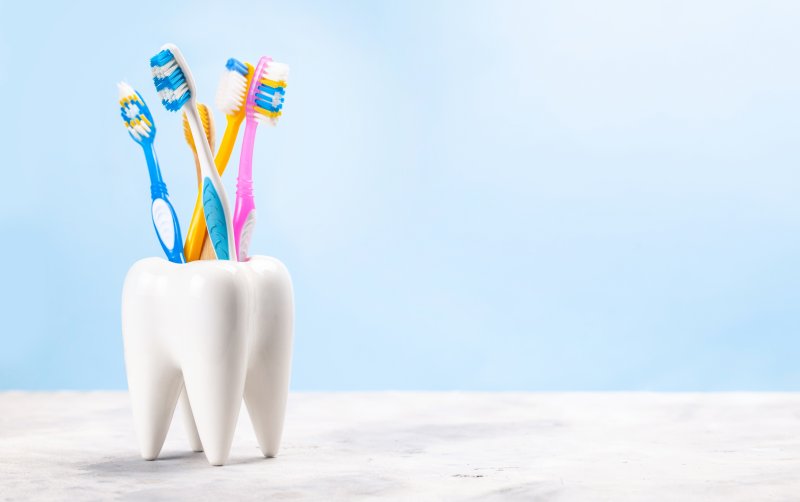 five toothbrushes sitting in a holder that looks like a tooth