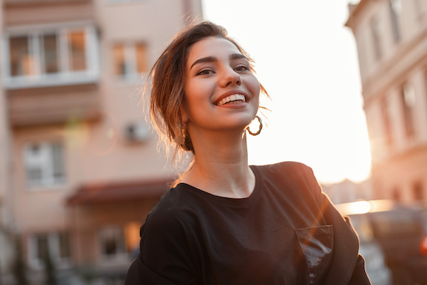 young woman smiling at sunset cityscape