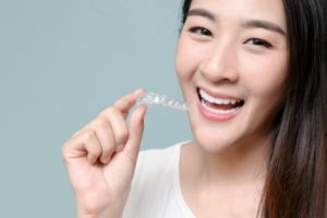 patient smiling and holding aligner after answering Invisalign questions