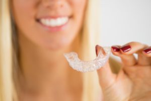 woman smiling and holding Invisalign
