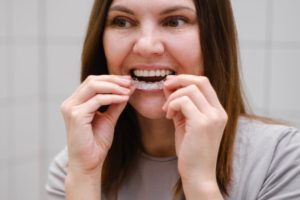 woman putting on Invisalign aligner