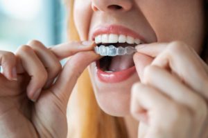 woman smiling while holding Invisalign 