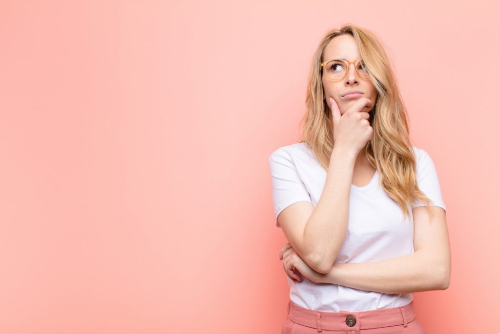 Closeup of woman wondering against pink wall