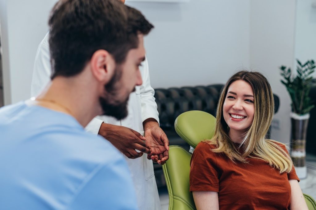Woman smiling while talking to dentist about Invisalign