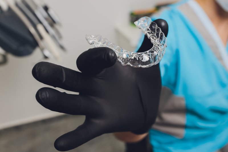 a dentist holding an Invisalign aligner